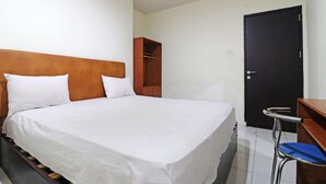 A hotel room with a bed, a wooden headboard, a wardrobe, a desk, and a door. - Anno Guesthouse (Makassar)