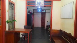 Un pasillo con un banco de madera a la derecha, una pequeña mesa con una silla a la izquierda y una puerta al final.