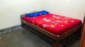 A small, single-bed room with a wooden frame and a red bedspread. - Losmen 2000 Tiga (Yogyakarta)