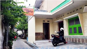 Un edificio con puerta verde, una motocicleta estacionada en frente y un letrero.