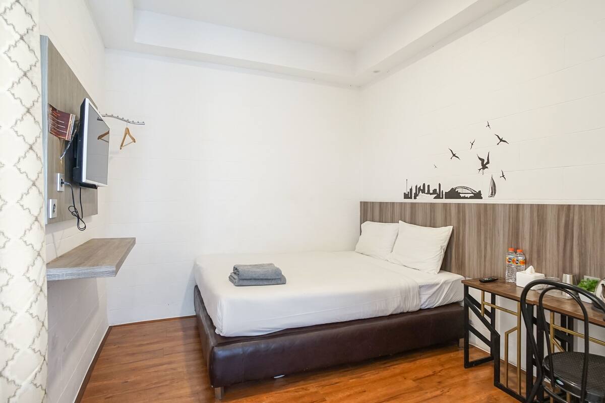 A compact hotel room with a bed, a desk, and a chair.