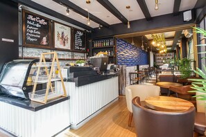 A café with a counter, seating area, and menu board. - Hotel Sanrina Makassar (Makassar)