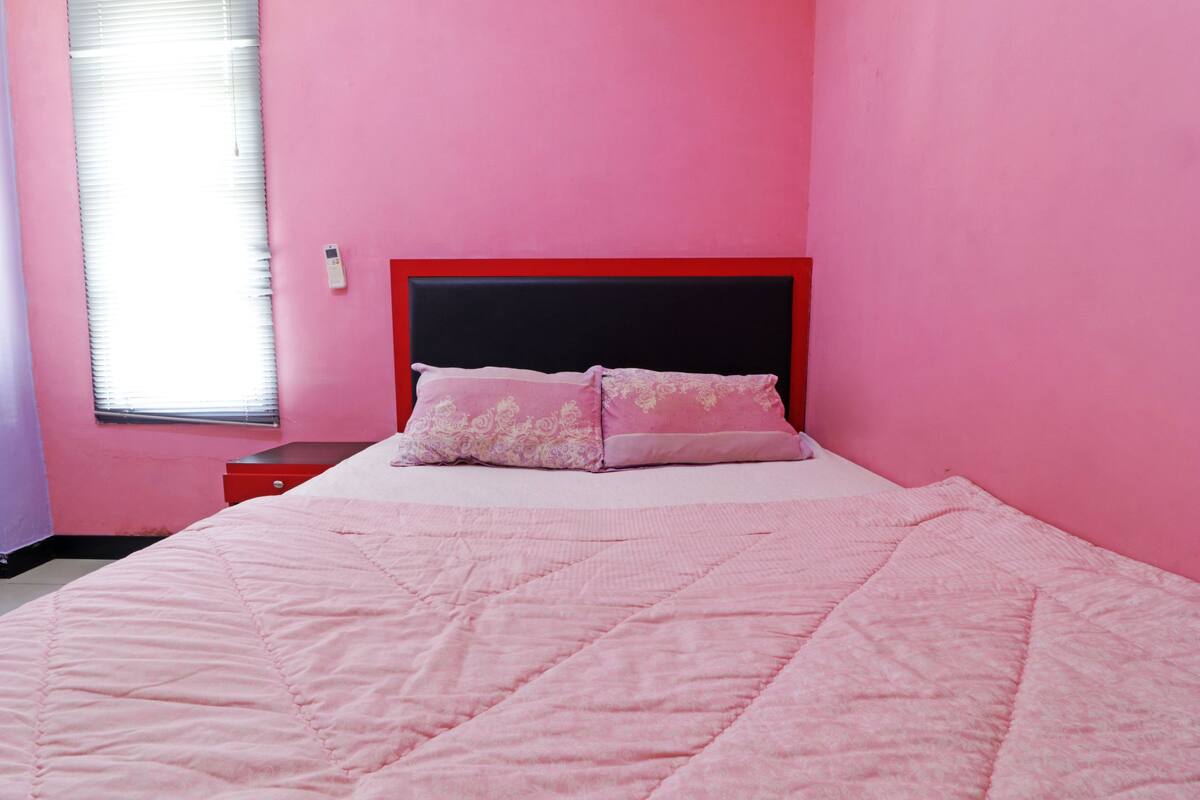 Een slaapkamer met een bed, een nachtkastje en een raam met zonwering.