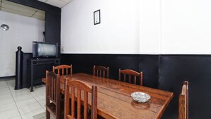 A dining area with a wooden table and chairs, a television on a stand, and a framed certificate on the wall. - Aurelia House A Mini Apartment (Pekanbaru)