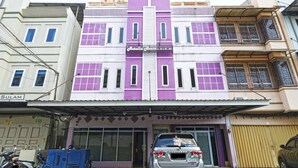 A multi-story building with a purple and white facade, a visible garage entrance, and a parked car. - Aurelia House A Mini Apartment (Pekanbaru)