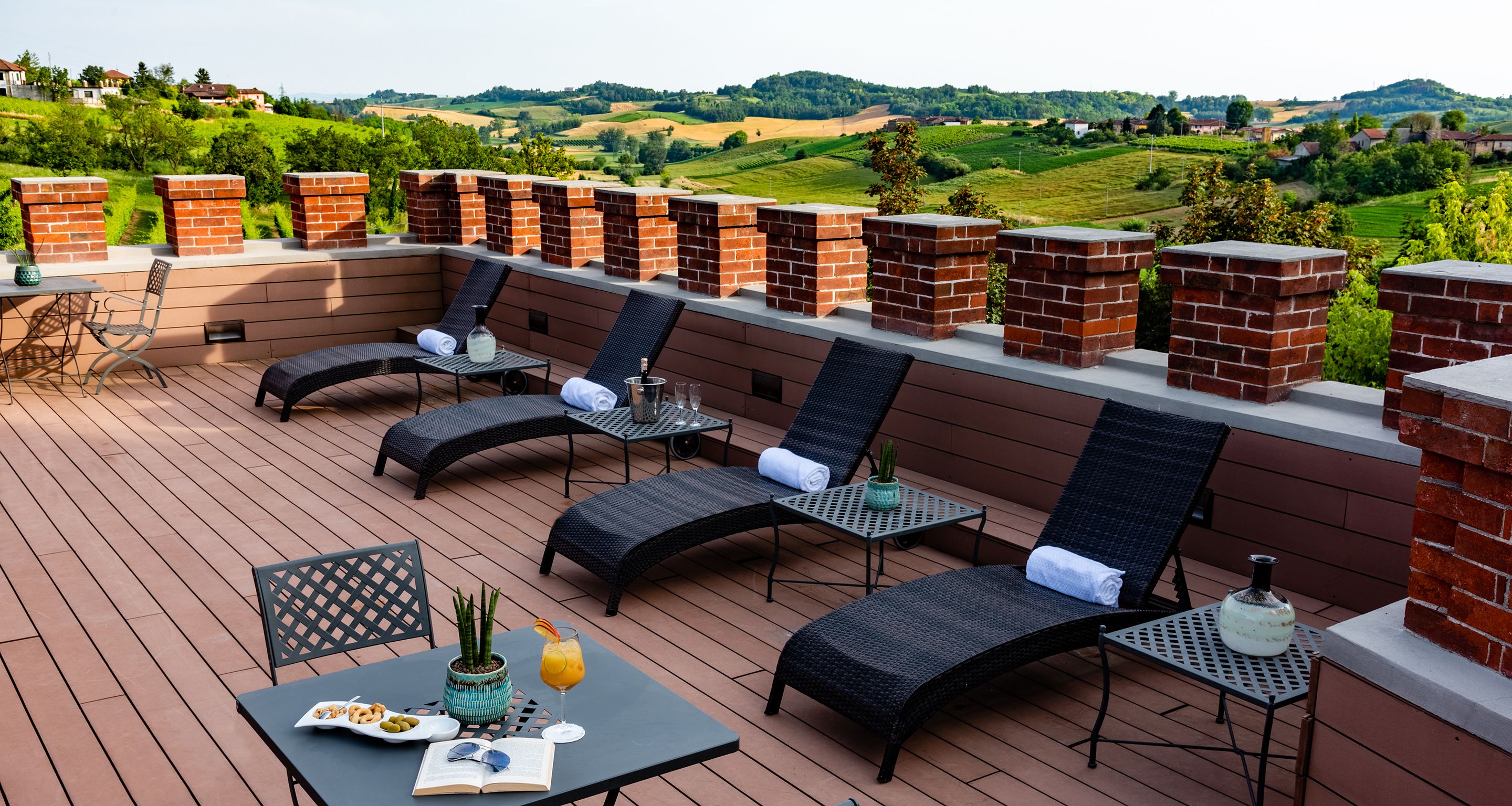 Eine Terrassenanlage im Freien mit Liegestühlen, einem Tisch und Blick auf die Landschaft.