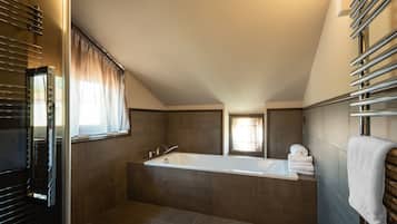 Un bagno moderno con una vasca da bagno ampia, una finestra con tende e un portasciugamani.