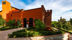 A modern building with a brick tower, a large entrance, and well-maintained landscaping. - Casa Munfrà (Penango)