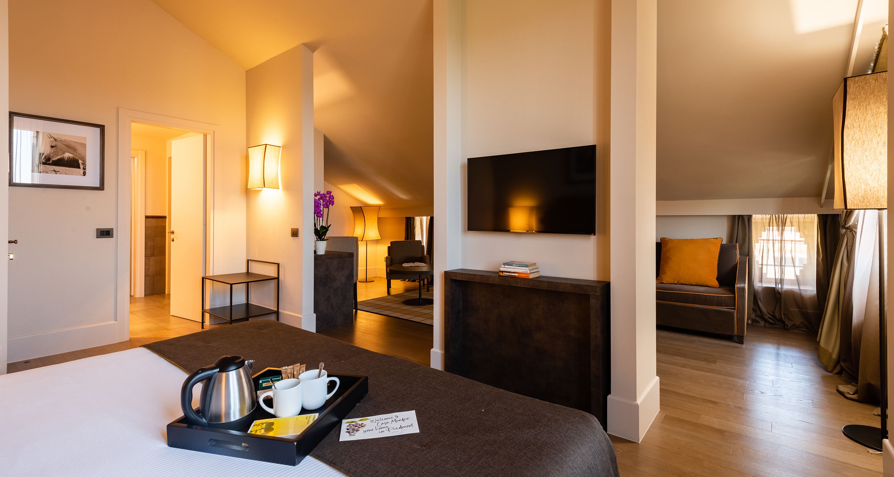 Ein Hotelzimmer mit Bett, Schreibtisch, Fernseher und Blick auf den Wohnbereich.