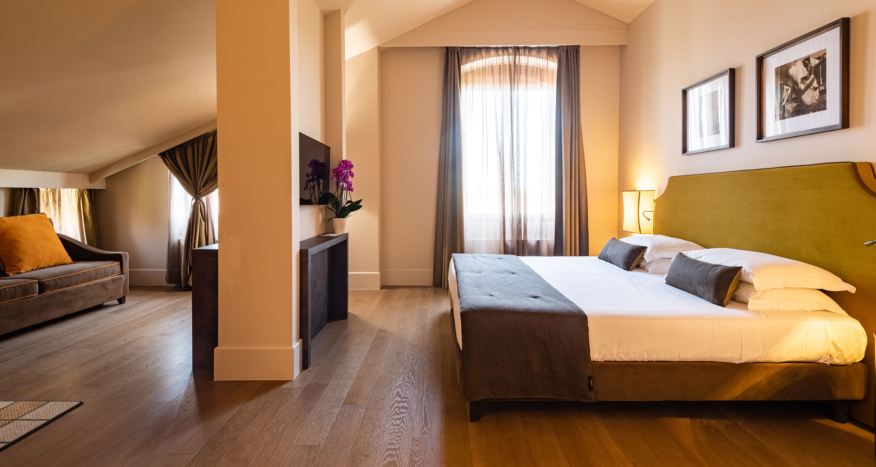 Een hotelkamer met een bed, een bank, een bureau en een raam met gordijnen.