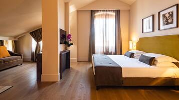 Een hotelkamer met een bed, een bank, een bureau en een raam met gordijnen.