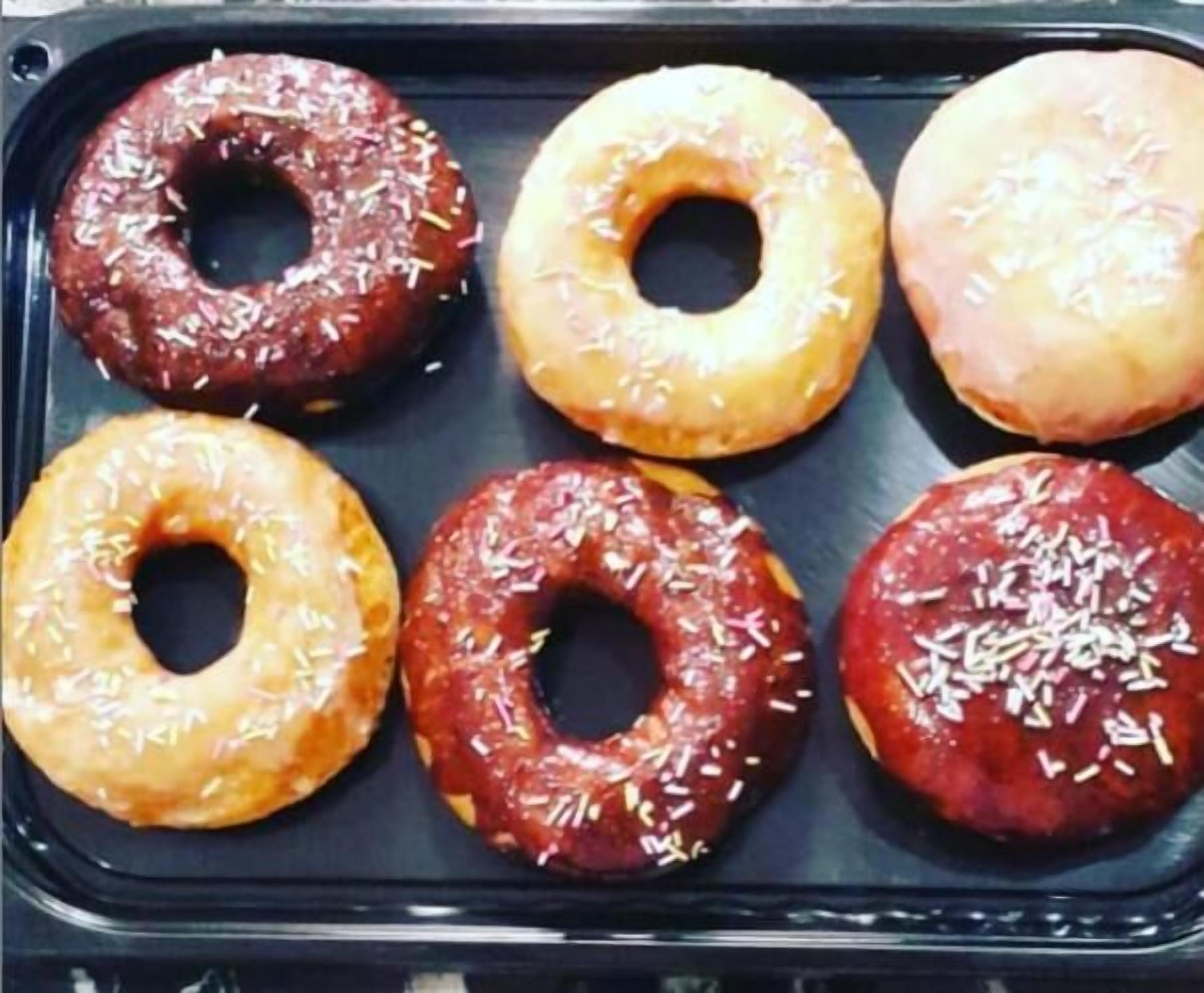 A tray of six glazed donuts with sprinkles.