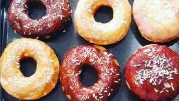 A tray of six glazed donuts with sprinkles.