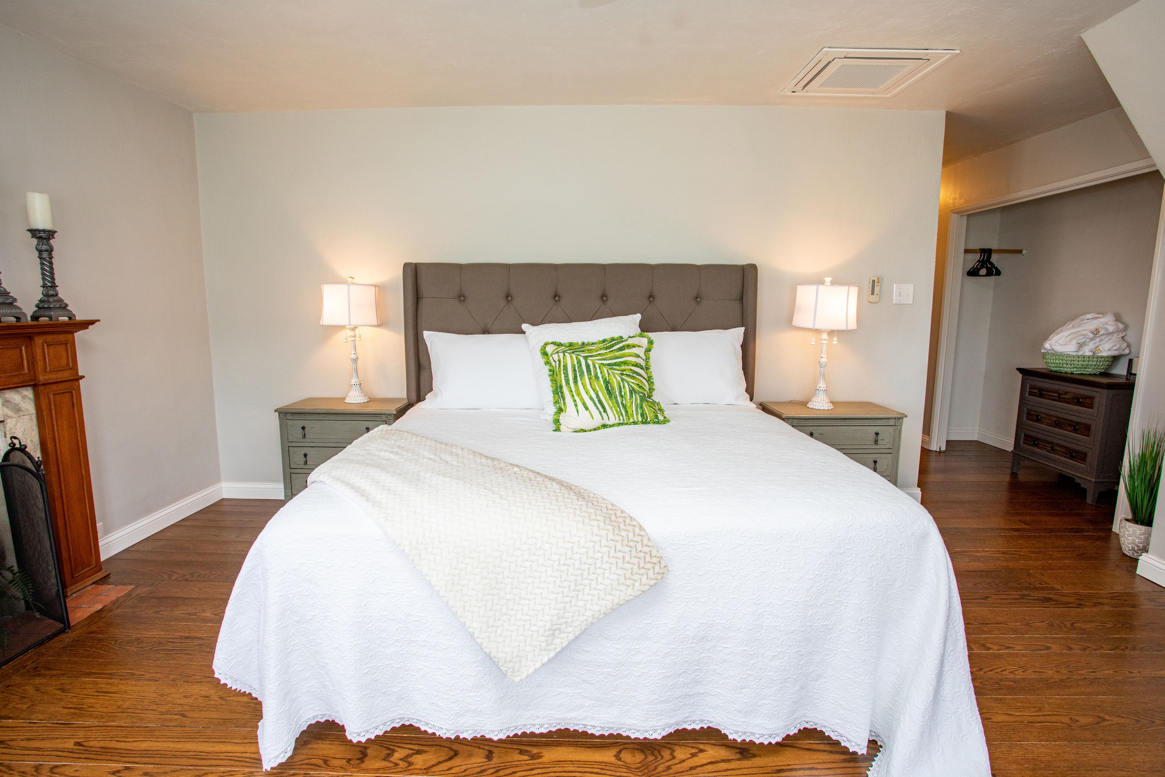 A neatly arranged bedroom with a large bed, two bedside tables, and a nightstand.