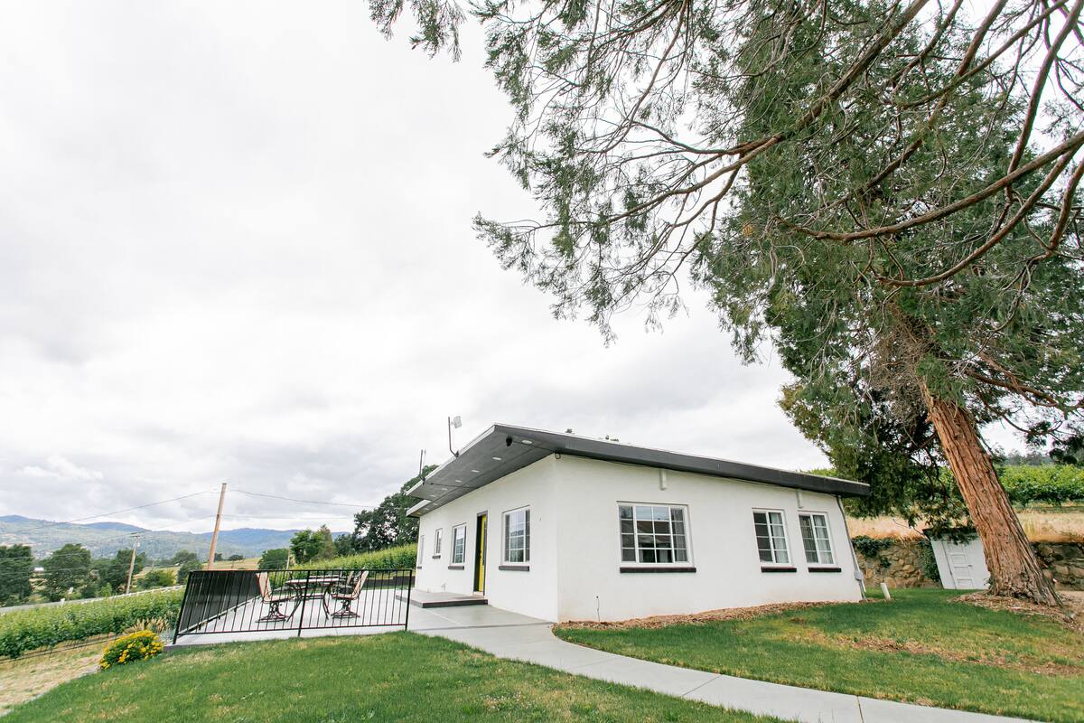 A white building with a flat roof, a small porch, and a paved driveway.