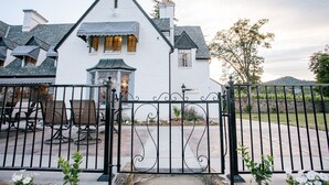 A white house with a black gate, outdoor seating, and a stone pathway. - Hummingbird Estate Wine & Suites (Central Point)