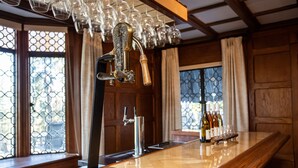 A bar area with a polished wooden counter, a tap with a handle, and a glass rack above. - Hummingbird Estate Wine & Suites (Central Point)