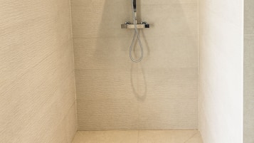 A modern shower with a square showerhead and a handheld shower attachment.