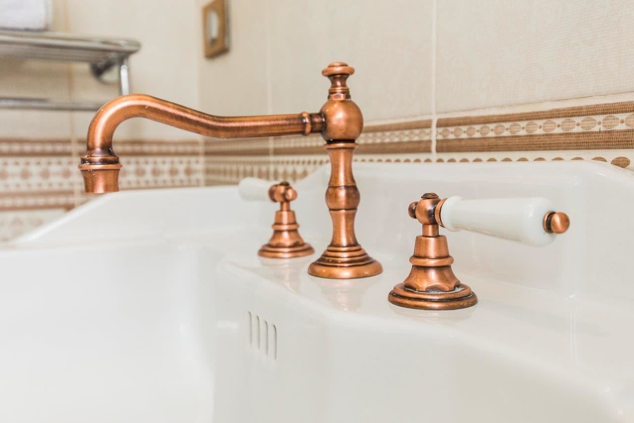 A bathroom sink with copper fixtures and a white basin.