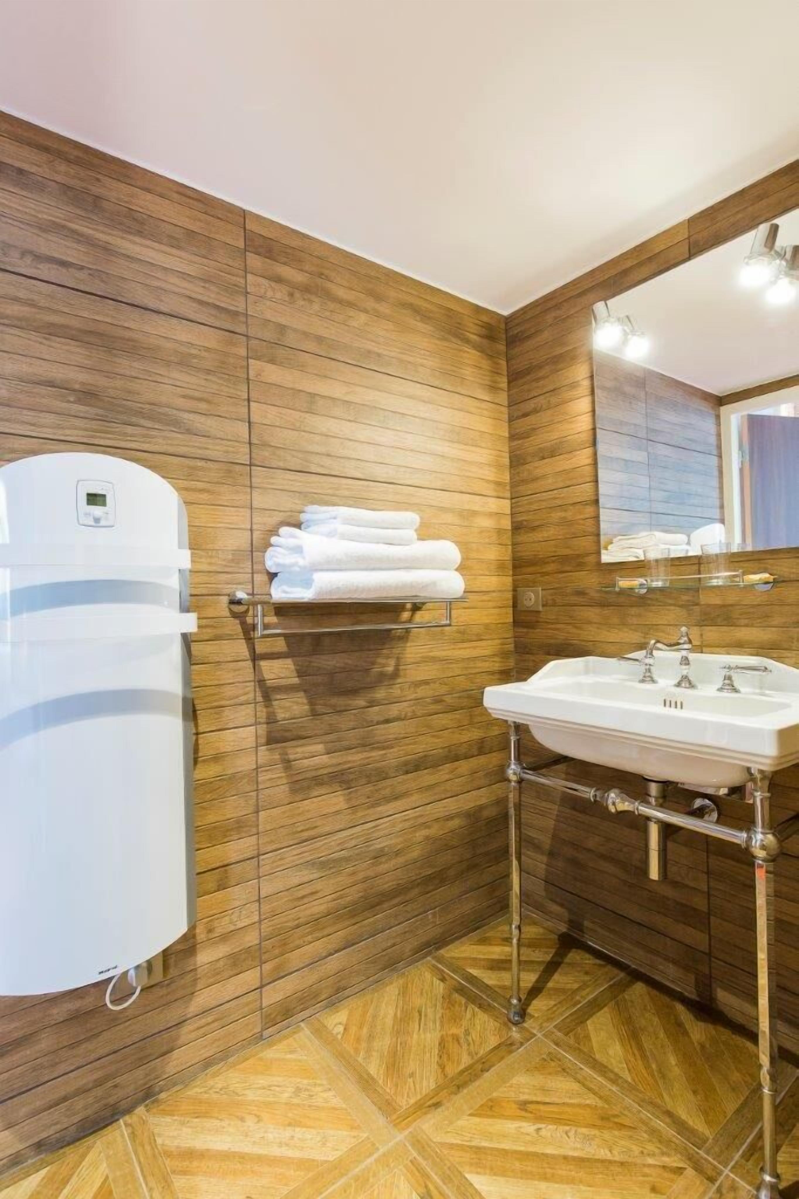 Une salle de bain moderne avec des murs recouverts de panneaux en bois, un lavabo blanc et un porte-serviettes.