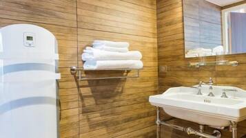 Une salle de bain moderne avec des murs recouverts de panneaux en bois, un lavabo blanc et un porte-serviettes.