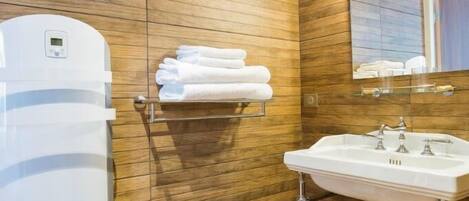 A modern bathroom with wooden panel walls, a white sink, and a towel rack.