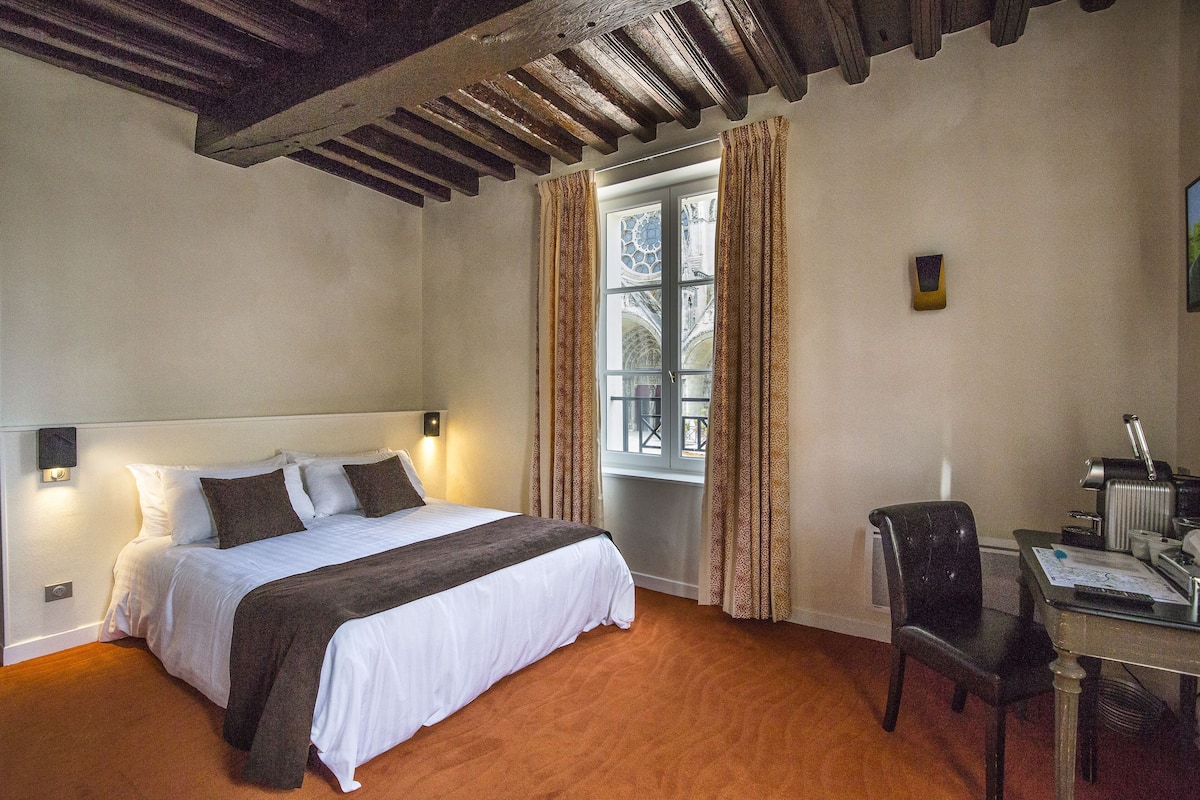 A bedroom with a bed, a desk, and a chair.