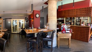 Un restaurant doté de banquettes en cuir, de tables en bois avec des chaises, et d’un bar avec une grande colonne.