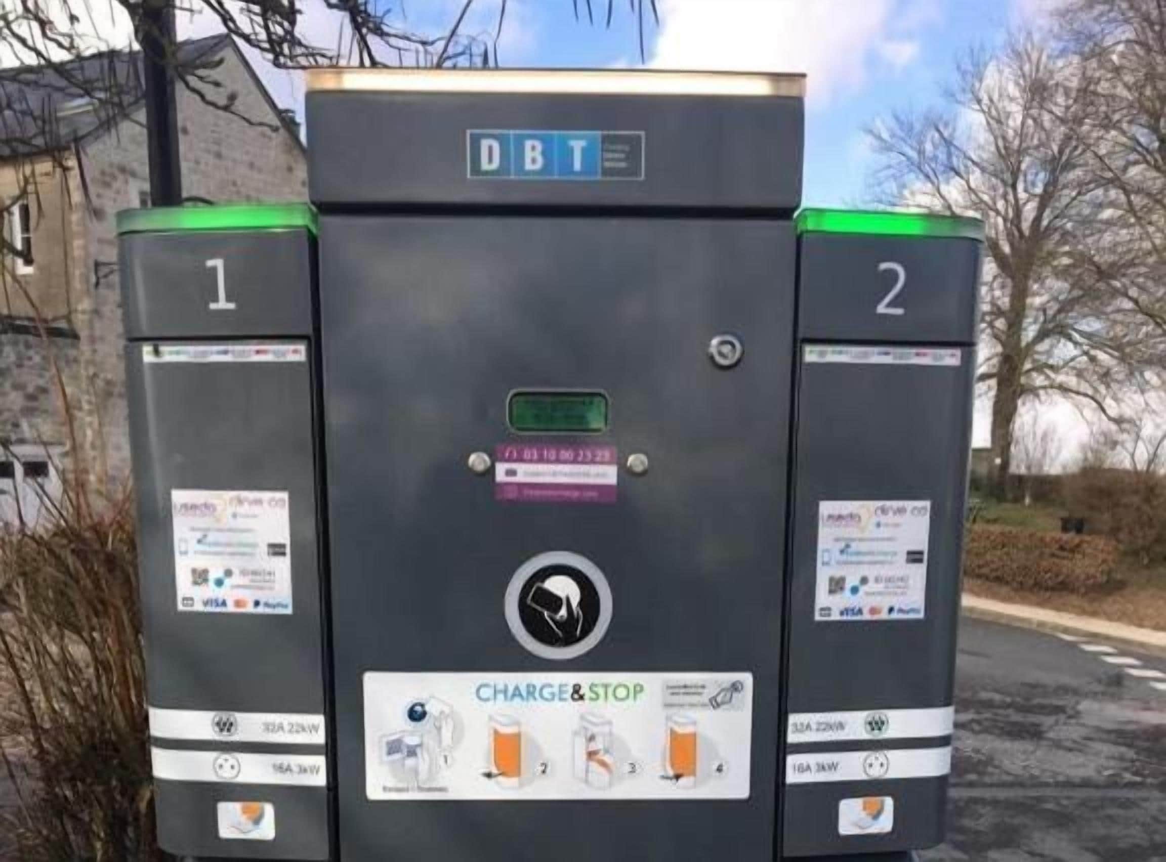 A DBT electric vehicle charging station with two charging points, a digital display, and payment options including VISA and MasterCard.