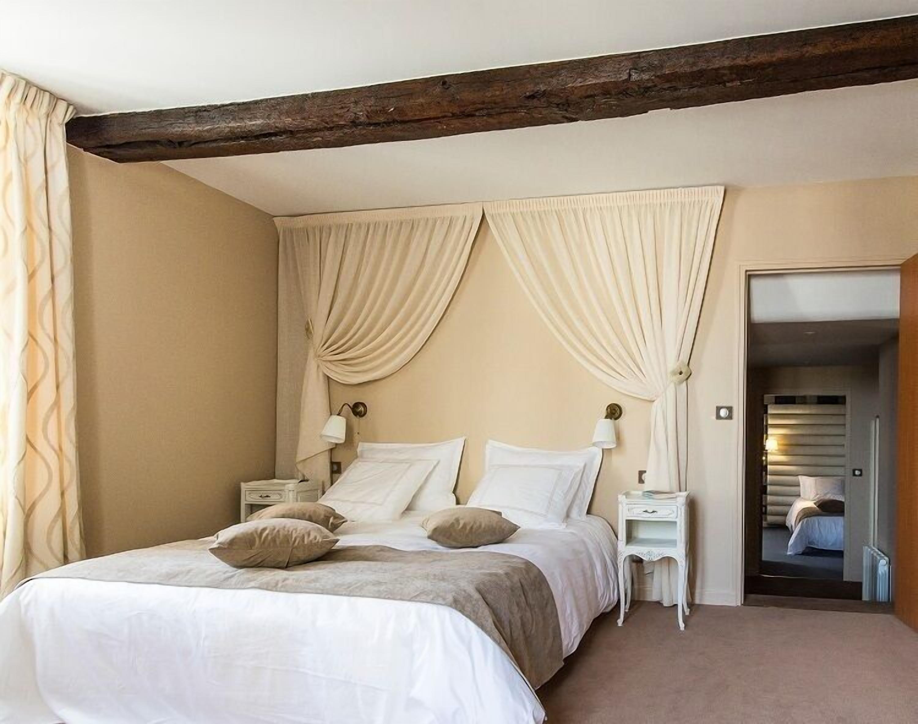 Un dormitorio con una cama grande, dos mesitas de noche y una puerta que da a otra habitación.