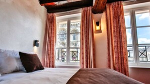 Une chambre d’hôtel avec un lit, une fenêtre avec des rideaux et une vue sur un immeuble doté d’un balcon.