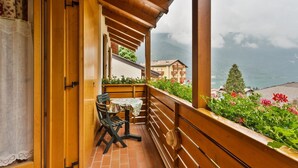 A wooden balcony with a table and chairs, overlooking a mountainous landscape and a body of water. - Residence Ronchi (Molveno)