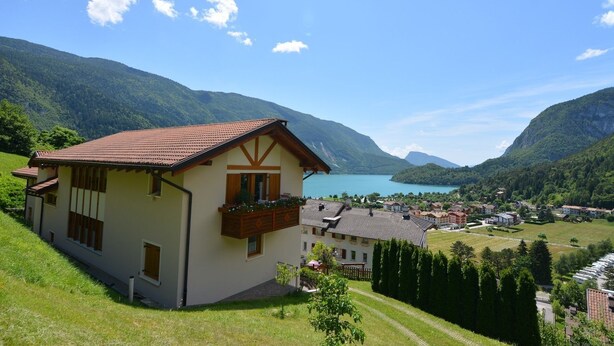 A house with a balcony overlooking a lake, surrounded by mountains and a small village. - Residence Ronchi (Molveno)