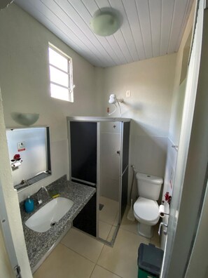 A compact bathroom with a sink, toilet, and shower stall.