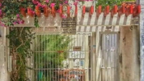 A gated entrance with a metal gate, a checkered floor, and a sign above the gate.