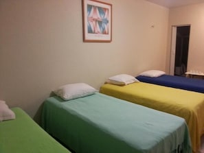A room with three single beds, each with a different colored bedspread.
