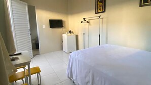 A bedroom with a bed, a desk, two chairs, a television, and a wardrobe.