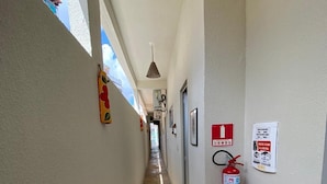 A narrow hallway with tiled flooring, a fire extinguisher mounted on the wall, and a ceiling light fixture.