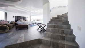 A spacious living area with a large bed, a sofa, and a staircase. - Air Lux (Mexico City)