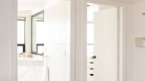 A modern bathroom with a white vanity, a large mirror, and a shower area. - Air Lux (Mexico City)