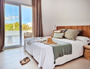 A bedroom with a bed, a balcony, and a view of greenery. - Apartaments Proa Es Pujols - Adults Only (Formentera)