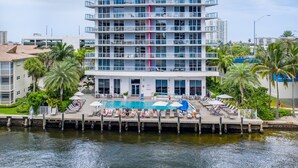 A multi-story hotel with a pool area, palm trees, and a waterfront view. - Resort Apartments (Hallandale Beach)