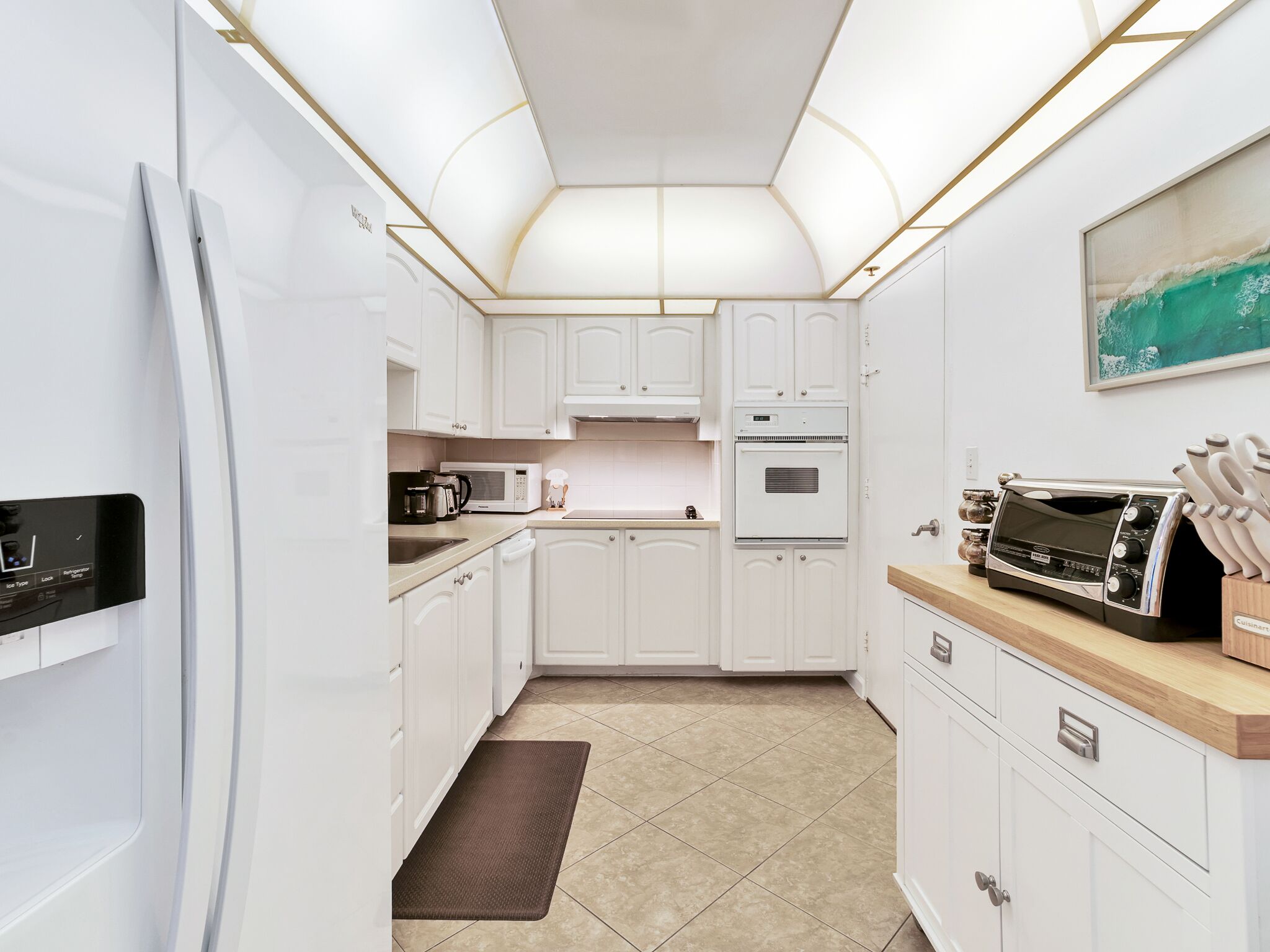 Une cuisine moderne avec des meubles blancs, un four à micro-ondes encastré, un four traditionnel et un grille-pain.