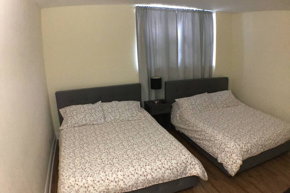 A twin room with two single beds, a nightstand with a lamp, and a window with curtains.