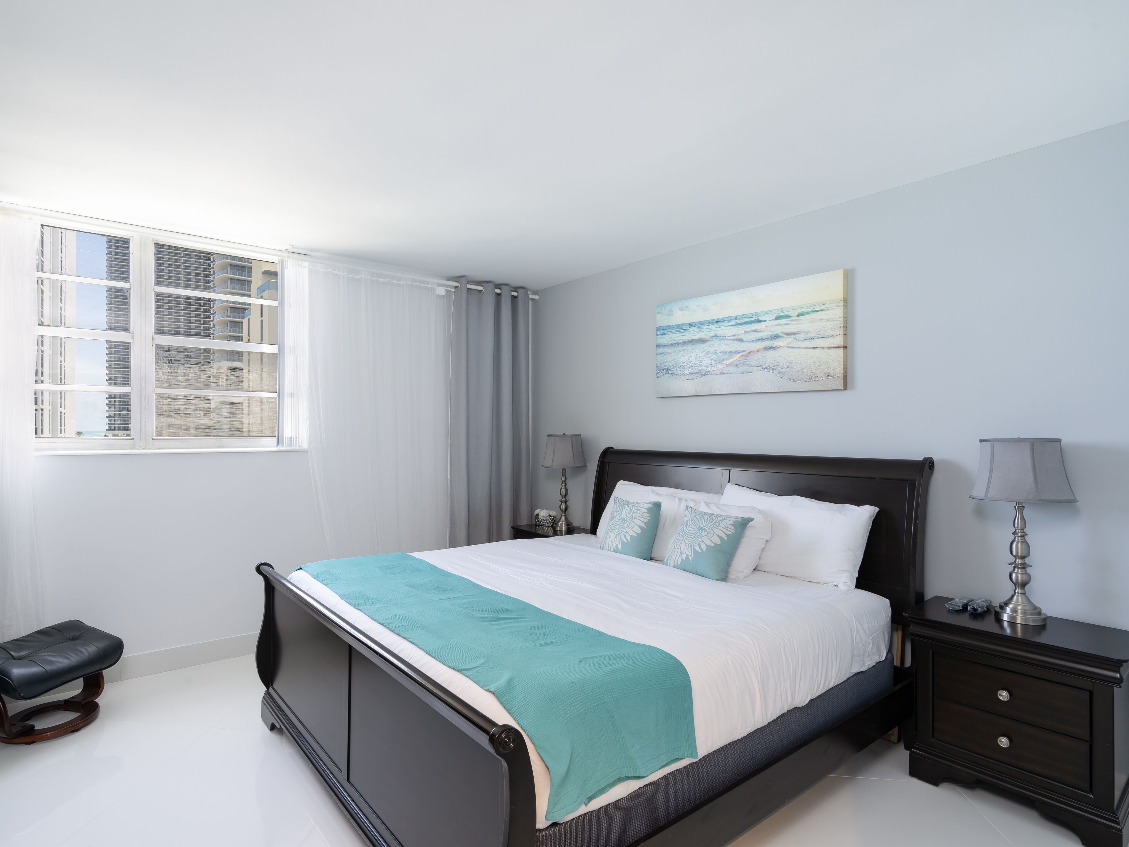 A modern bedroom with a bed, bedside tables, and a window with curtains.