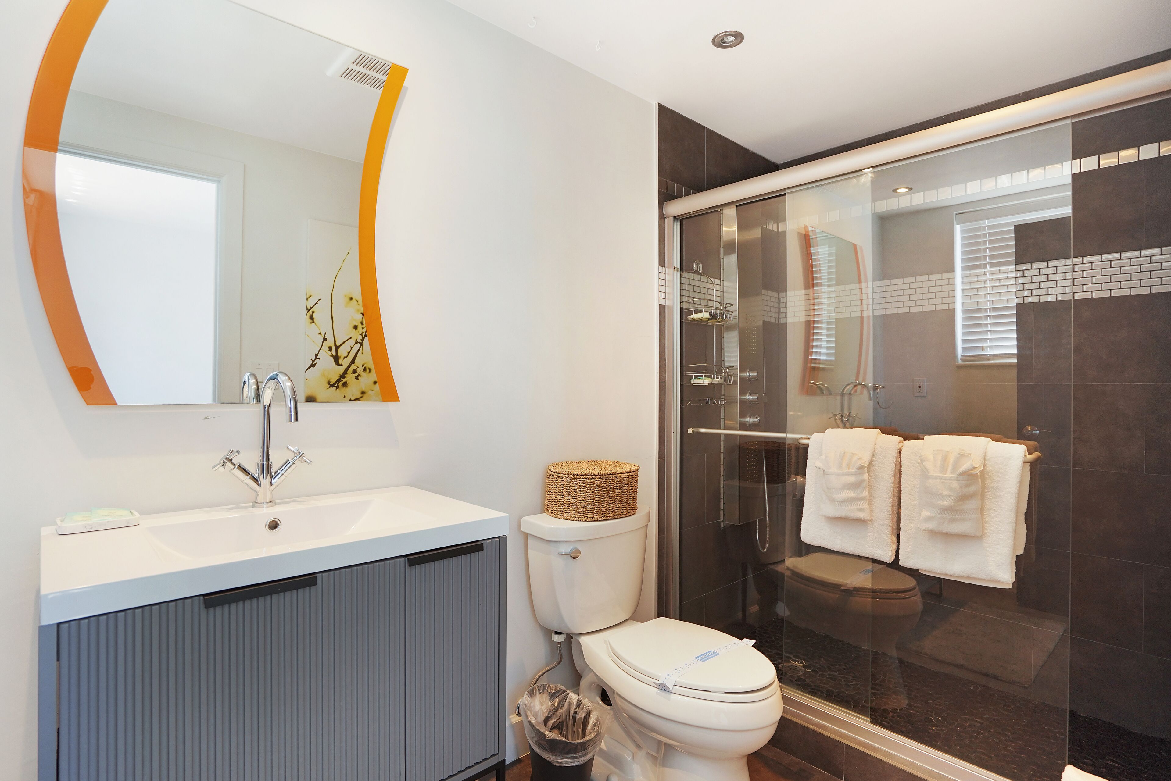 A modern bathroom with a white sink, a toilet, and a glass-enclosed shower area.