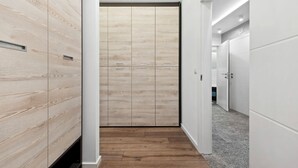 Ein Flur mit Holzvertäfelung, einem zentralen Kleiderschrank mit mehreren Fächern und einem grauen Fliesenboden.