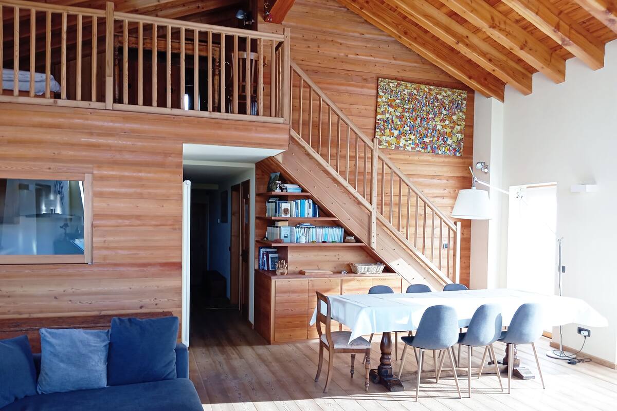 A wooden interior with a staircase, a dining area, and a sofa.