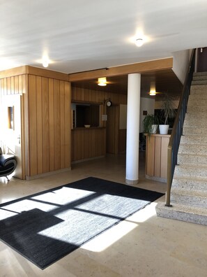 Un interior espacioso con paneles de madera, una alfombra negra, una escalera y un reloj en la pared.