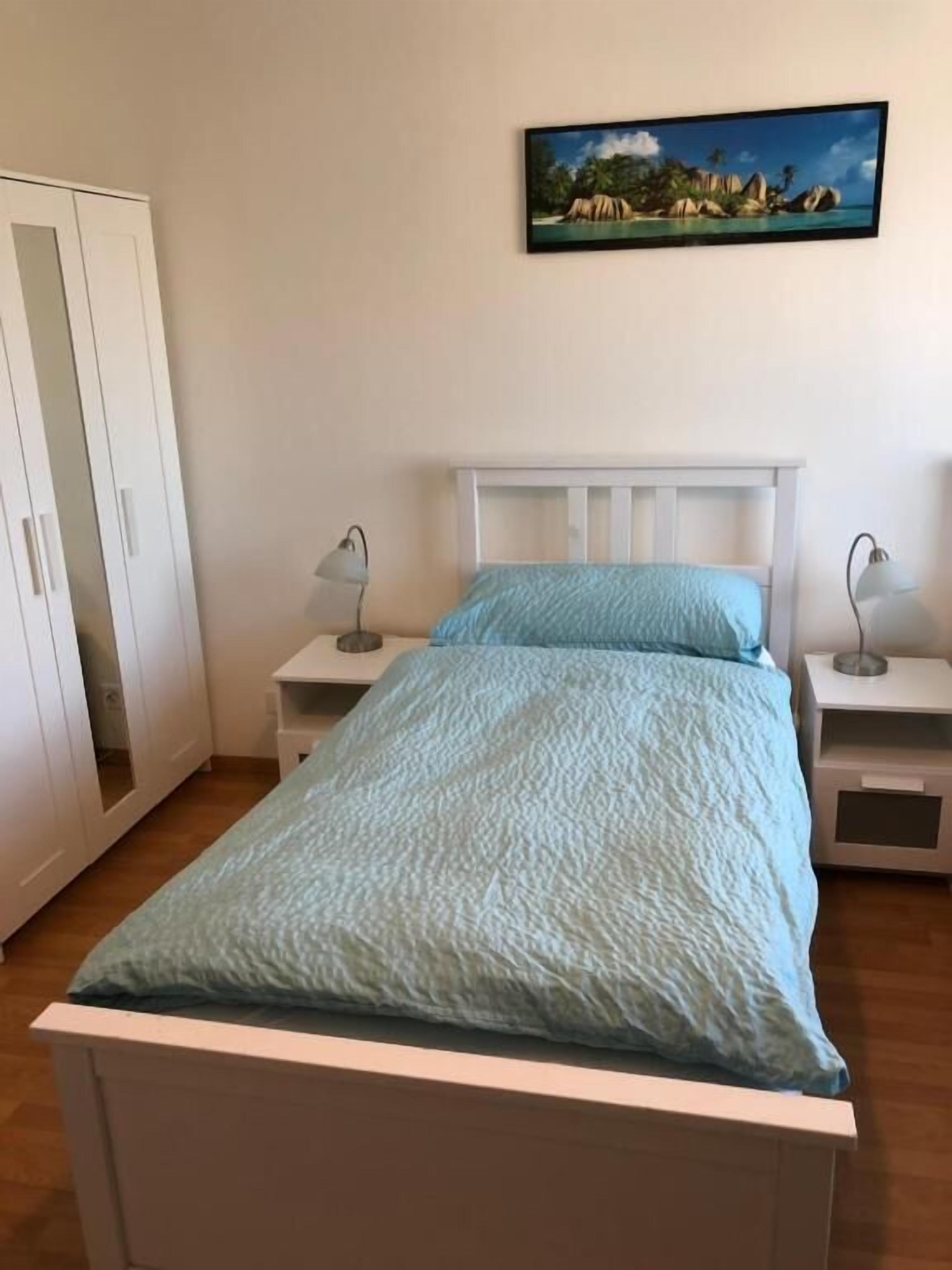 Une chambre à coucher comprenant un lit, deux tables de chevet, une armoire et un tableau encadré accroché au mur.